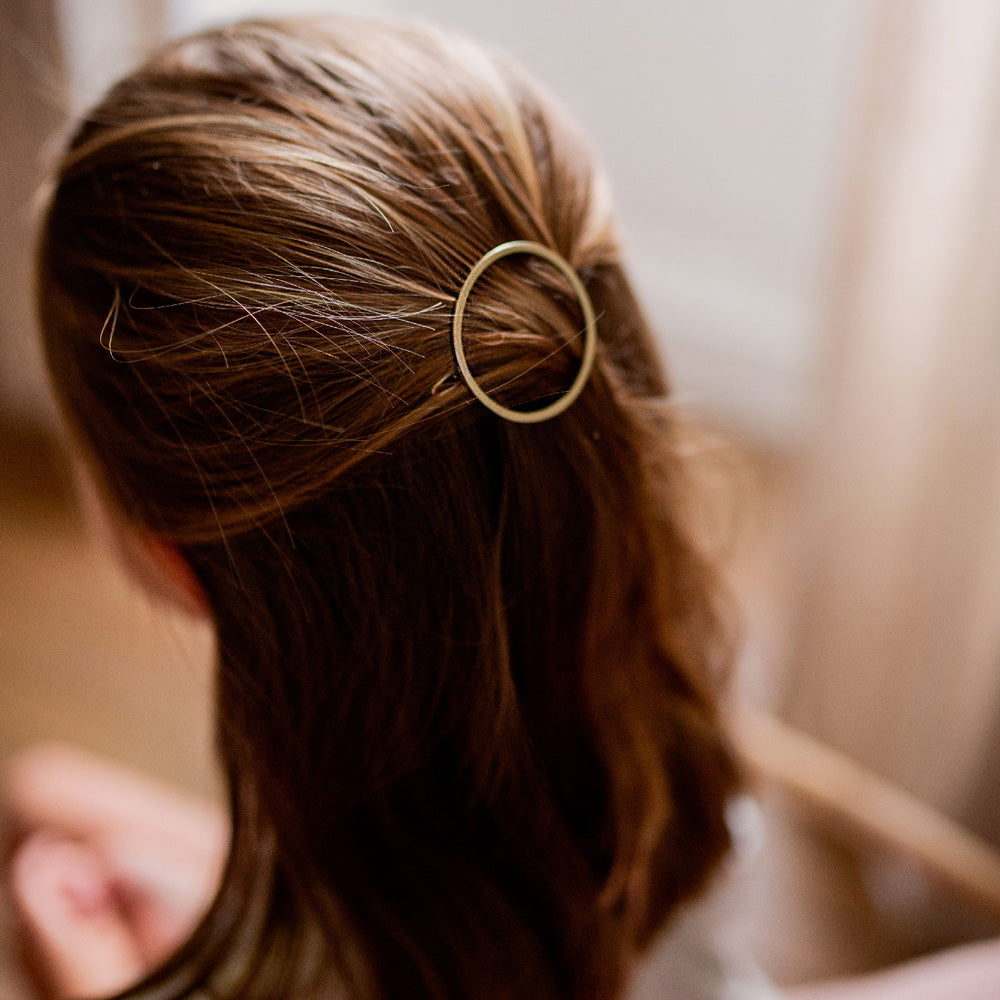 Barrette ronde dorée Bachca Emma fixée dans des cheveux châtains, coiffure élégante et minimaliste.