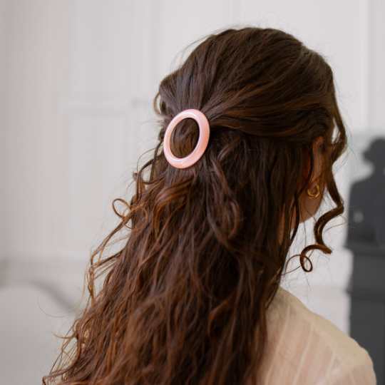 Coiffure demi-queue bohème avec barrette ronde rose dragée Bachca, accessoire chic et féminin.