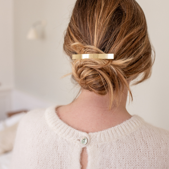 Chignon bas élégant maintenu par une barrette rectangulaire dorée Bachca, coiffure raffinée et naturelle.