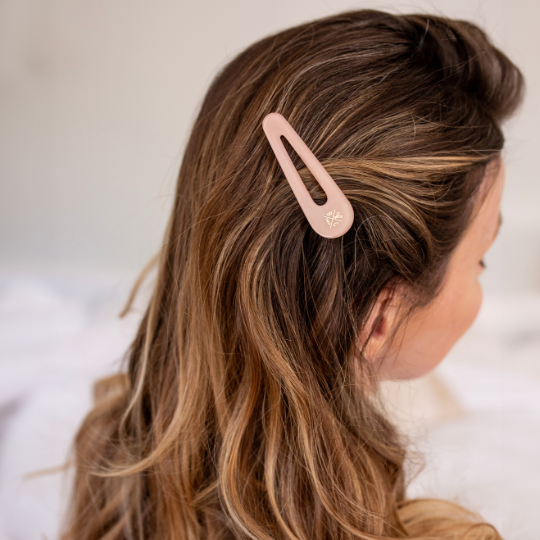 Barrette rose dragée Bachca fixée sur le côté, accessoire élégant pour sublimer une coiffure naturelle.