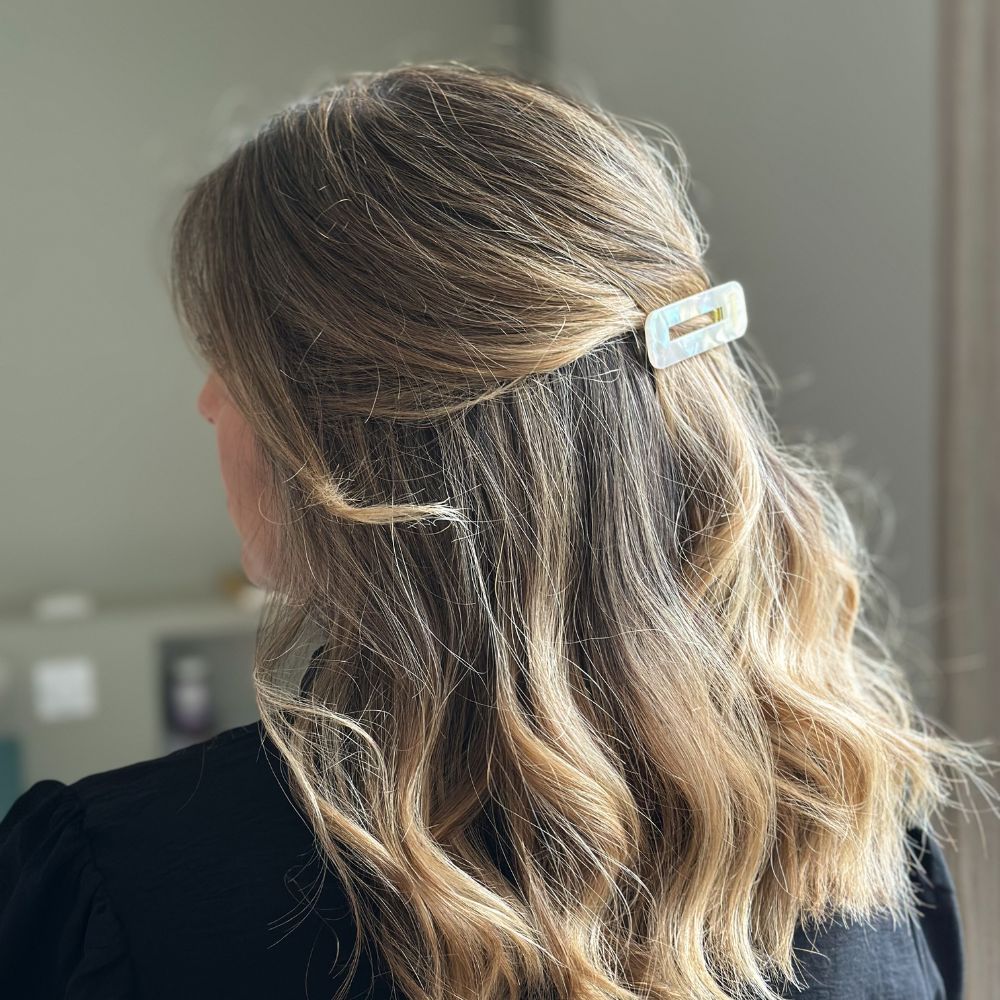 Cheveux ondulés blonds attachés avec une barrette rectangulaire nacrée Bachca, vue de dos élégante.