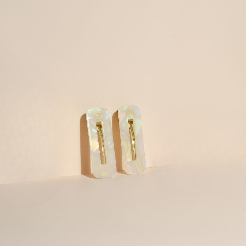 Duo de barrettes rectangulaires Bachca en acétate effet nacre, posées sur fond beige, accessoire chic et minimaliste.