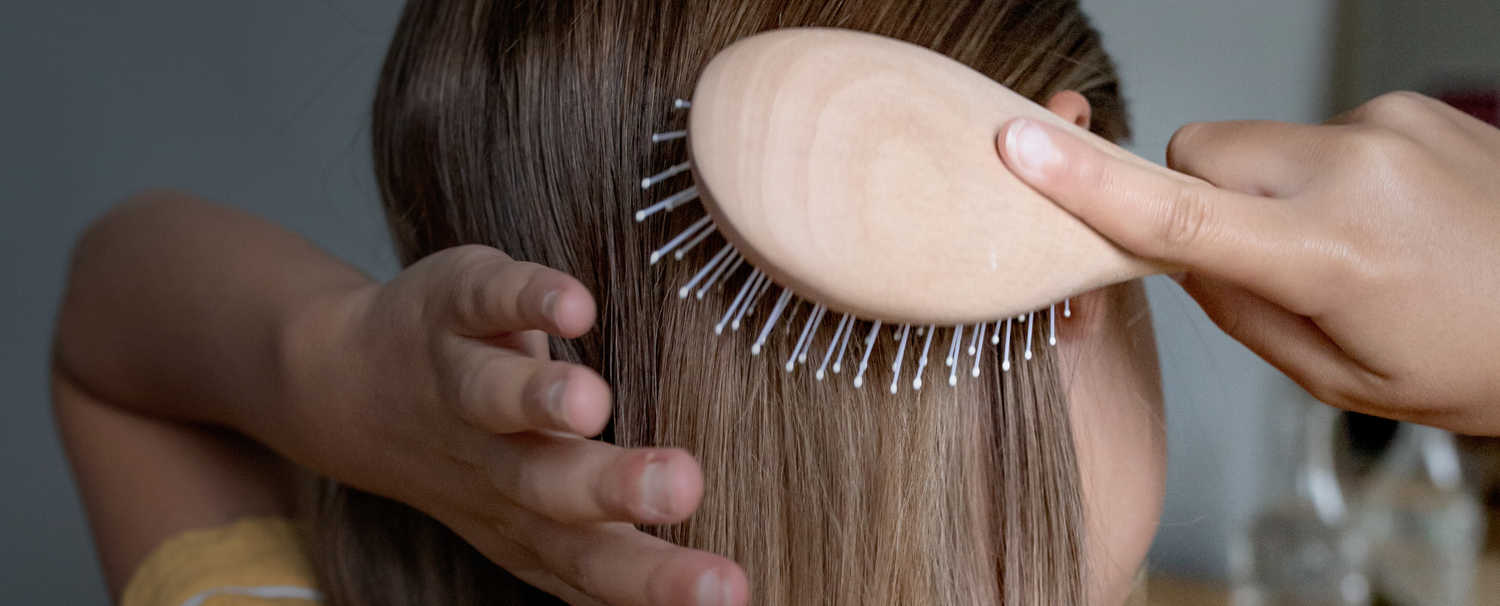 Jeune fille de dos se brossant les cheveux à l'aide d'une brosse de la marque Bachca.