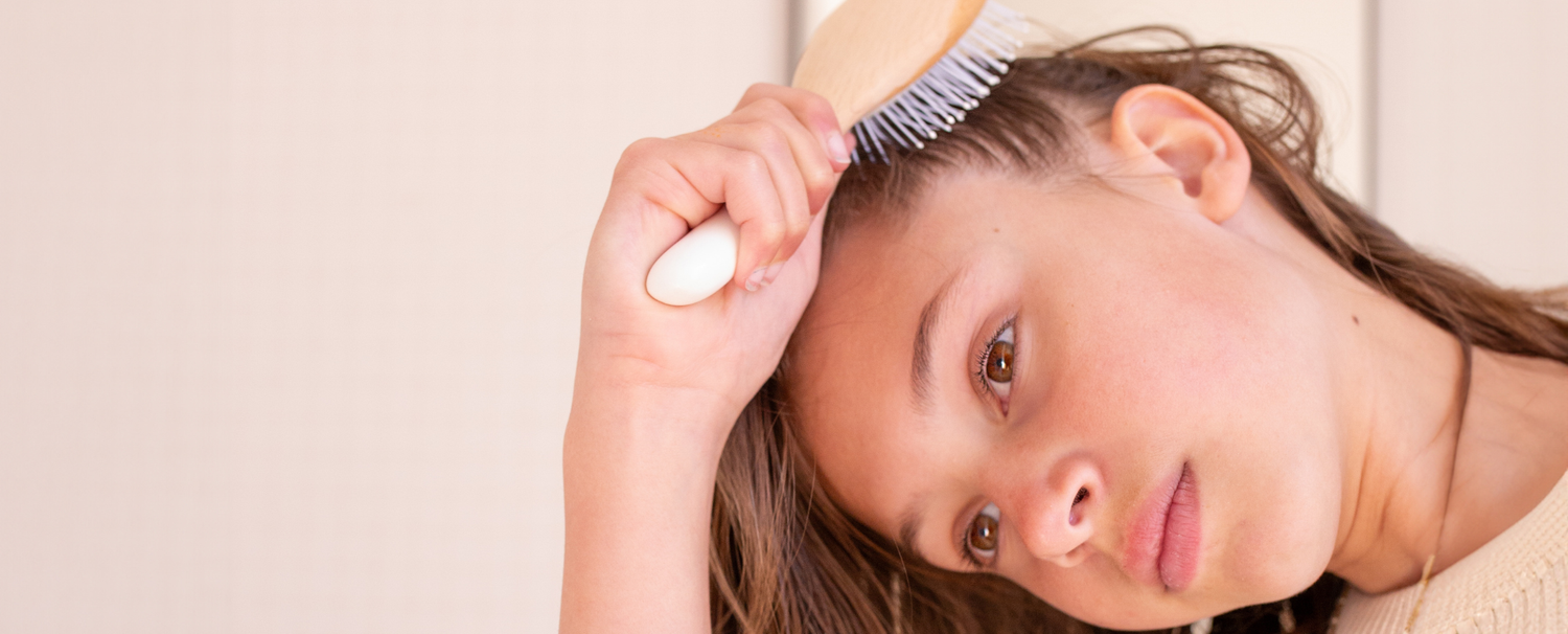 Jeune fille se démêlant les cheveux avec une brosse à cheveux de la marque Bachca.