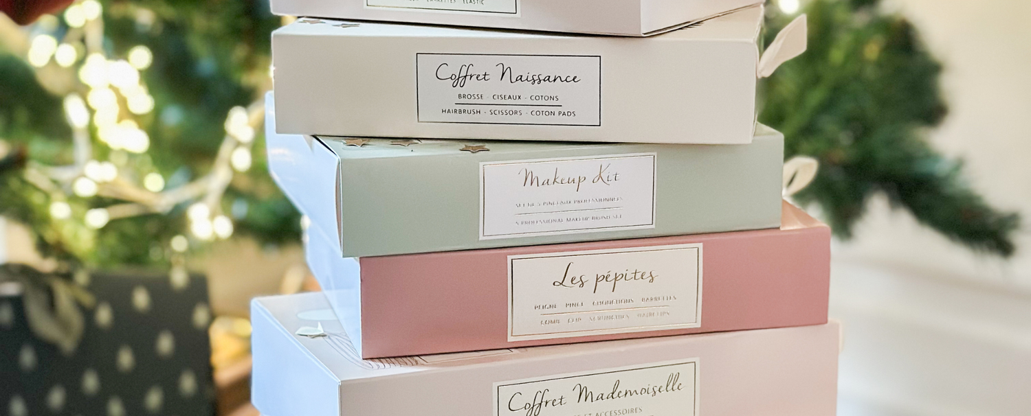 Coffrets d'accessoires de la marque Bachca empilés devant un sapin de noël.