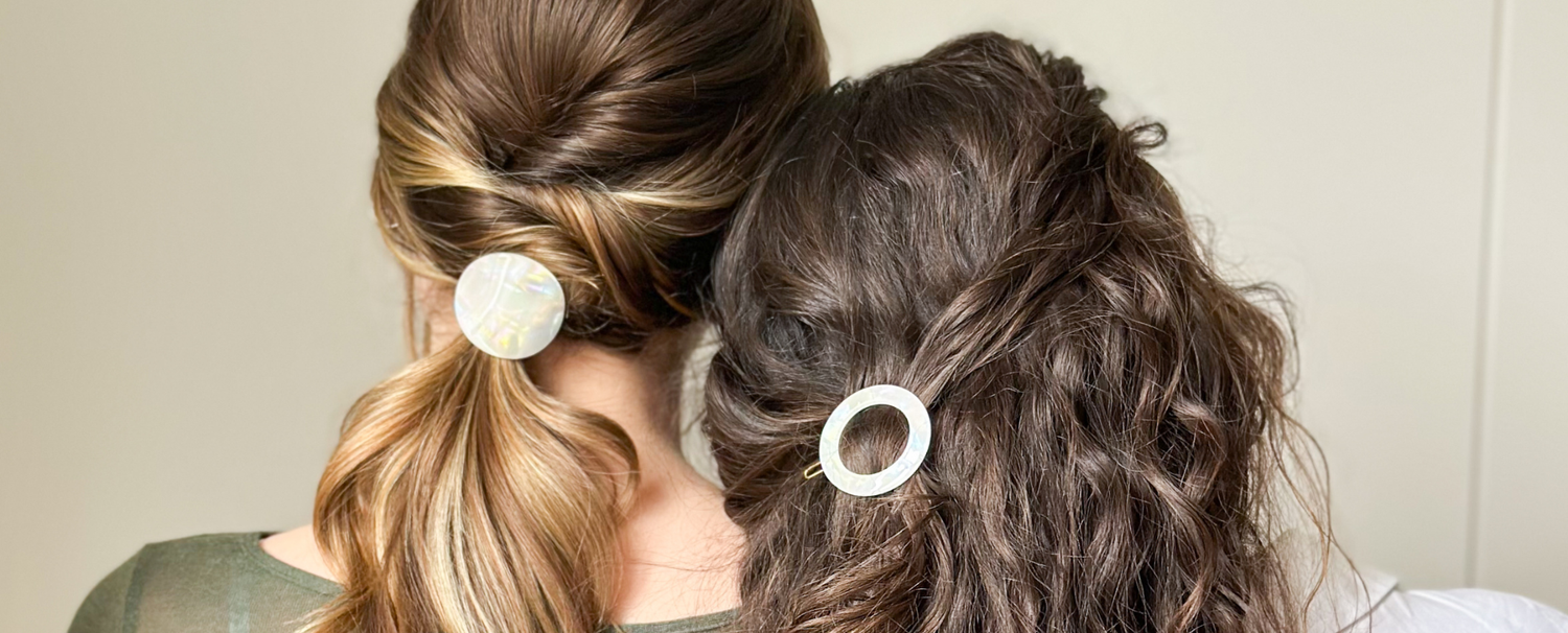 Deux femmes aux cheveux différents de dos portant dans leurs cheveux des accessoires nacrés de la marque Bachca.