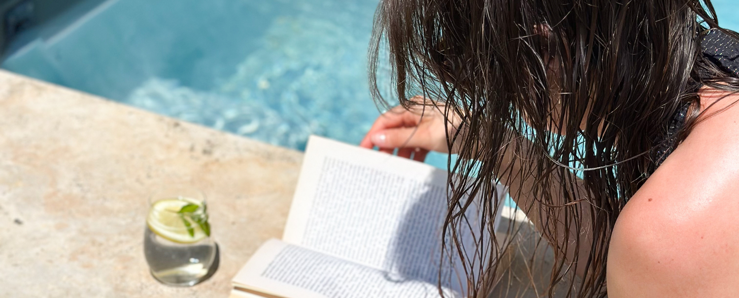 Femme lisant un livre sur le bord d'une piscine.