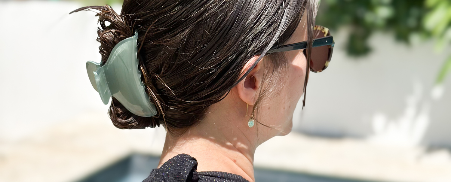 Femme de dos avec le cheveux mouillés attachés à l'aide d'une grande pince à cheveux vert d'eau de la marque Bachca.