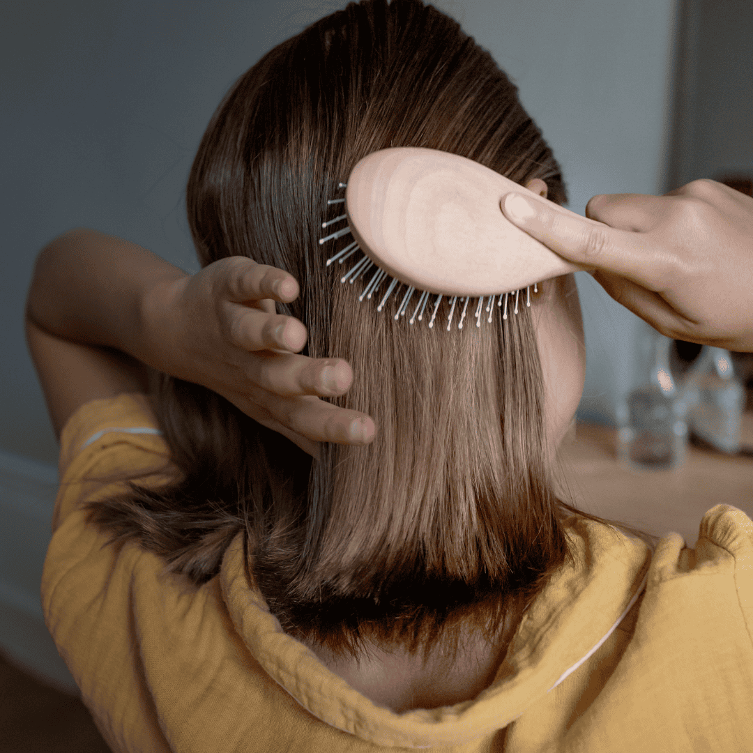 Enfant se brossant les cheveux avec une brosse Bachca à picots nylon sur cheveux lisses, dans une ambiance douce et naturelle.