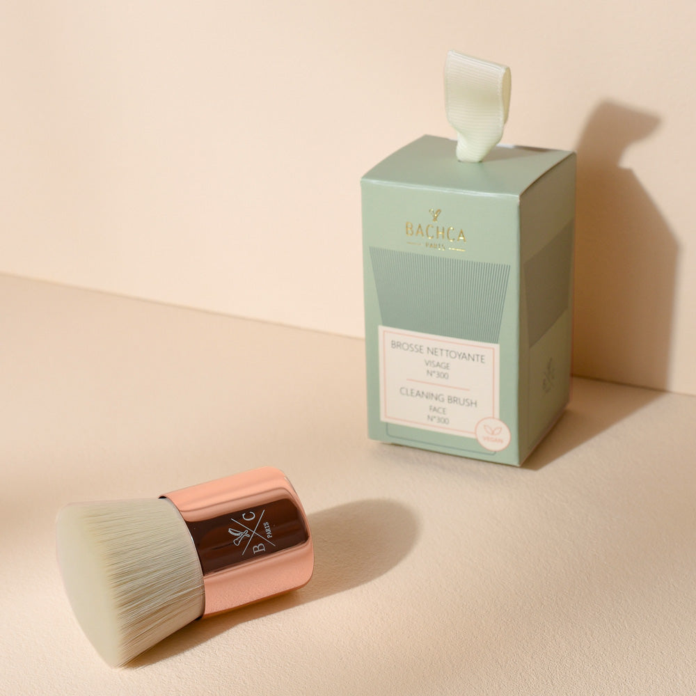 Brosse nettoyante visage Bachca grand format avec poils ultra-doux et manche doré rosé, accompagnée de son coffret élégant vert sauge.