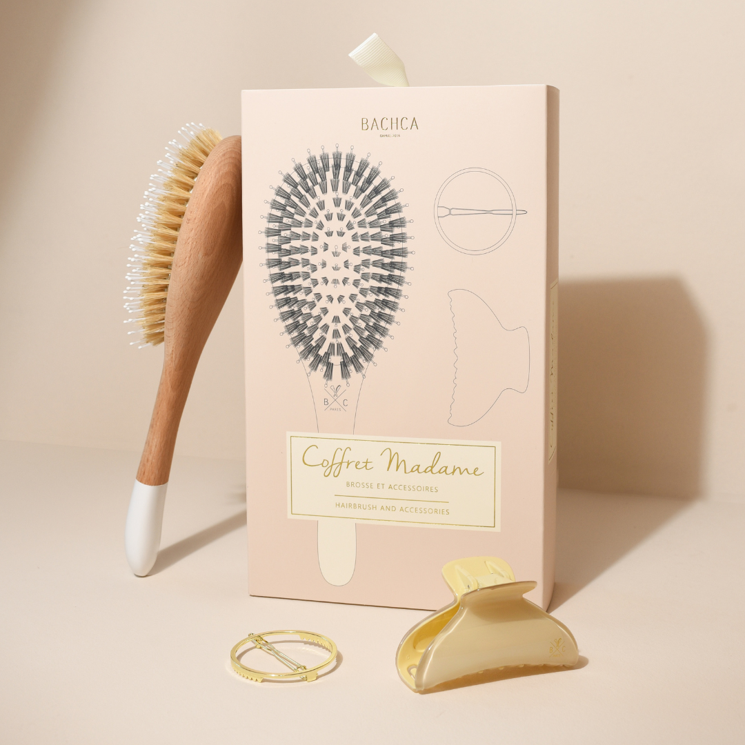 Coffret Madame Bachca contenant une brosse en bois à picots nylon et sanglier, une pince crème et une barrette dorée, présenté devant son étui illustré sur fond beige.