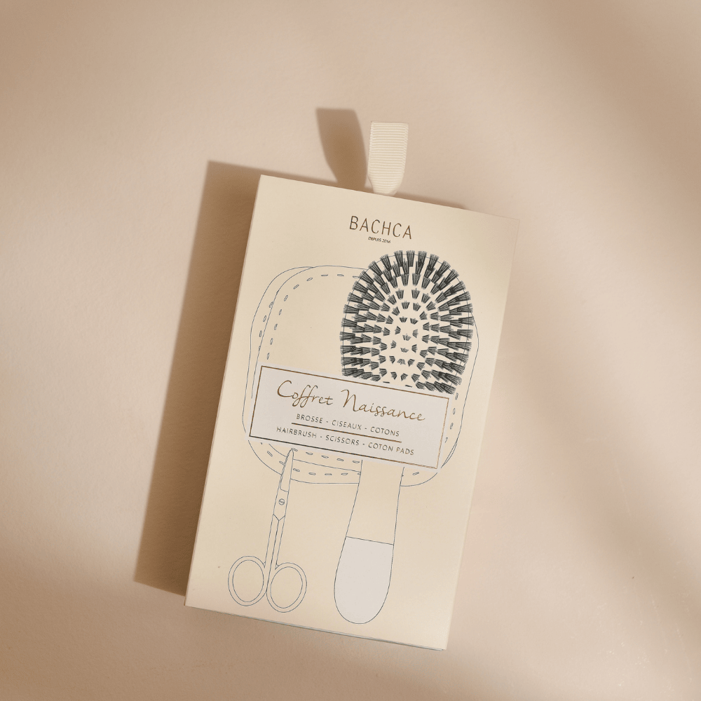Packaging du coffret naissance de la marque Bachca posé sur un fond studio rose pâle.