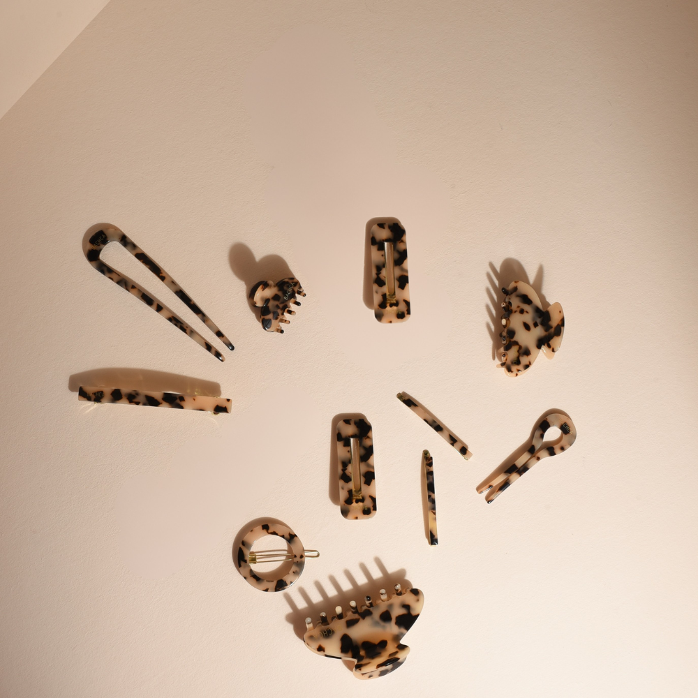 Accessoires cheveux écailles réunis sur un fond studio rose pâle.