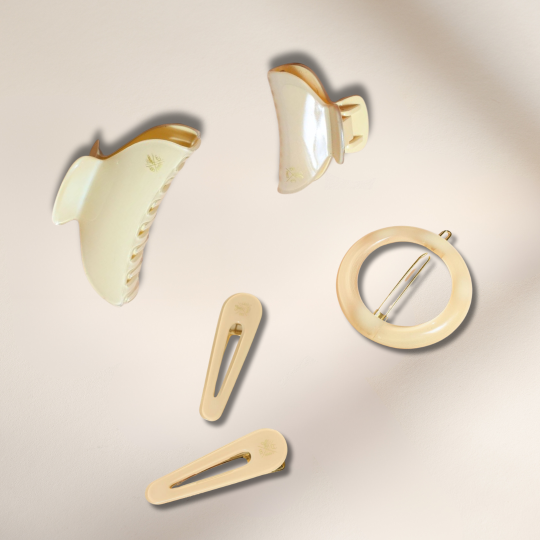 Accessoires de la collection ivoire, pinces et barrettes réunis sur un fond studio rose pâle.