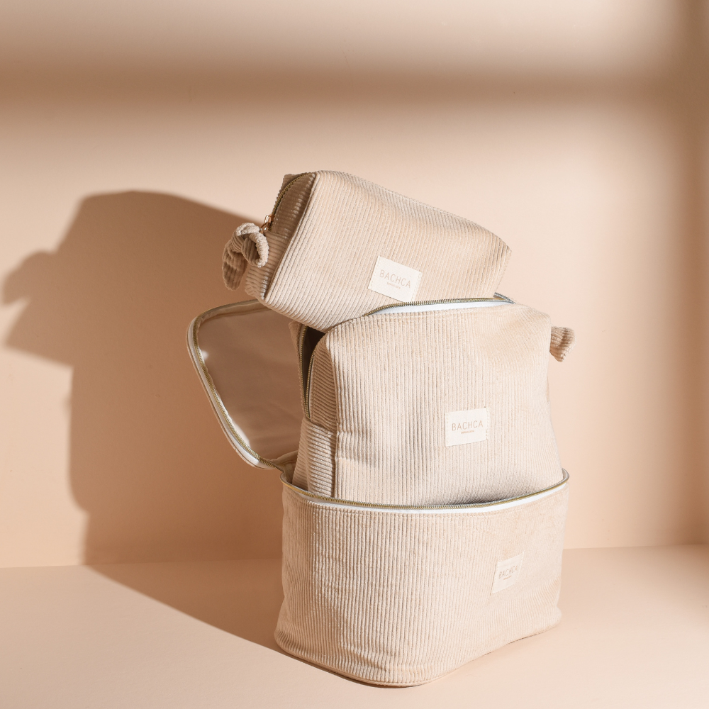 Collection de trousses BACHCA en velours beige empilées, lumière naturelle sur fond crème.