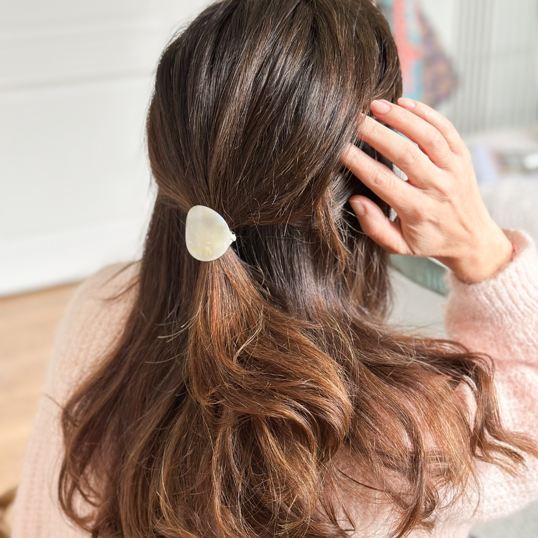 Femme portant un élastique plaque nacré Bachca dans ses cheveux ondulés, demi-attache naturelle dans une lumière douce.