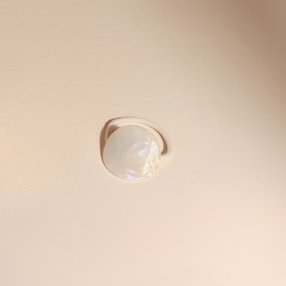 Élastique cheveux plaque nacre Bachca posé sur fond beige, accessoire élégant en acétate de cellulose.