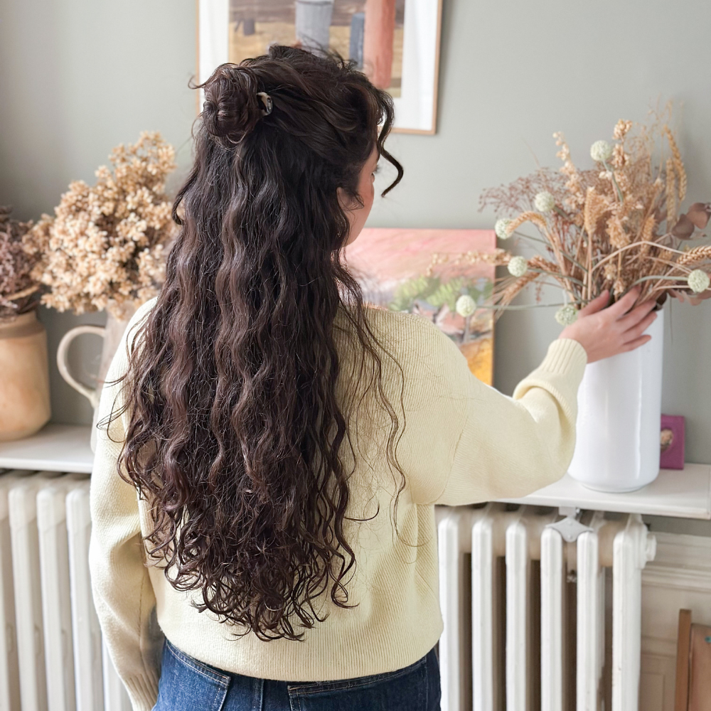 Femme de dos dans son salon avec les cheveux attachés en demi-chignon à l&