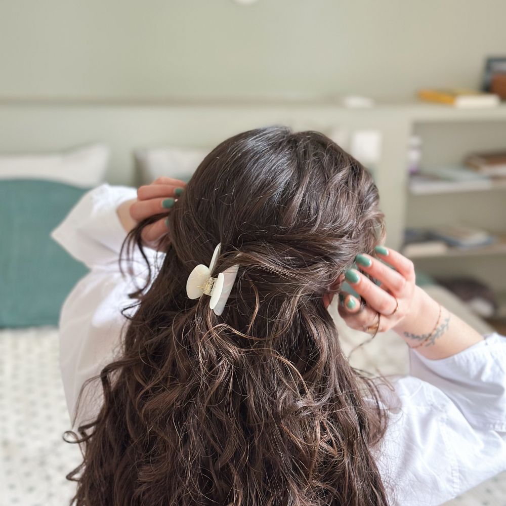 Cheveux bouclés attachés avec pince nacrée Bachca, coiffure élégante et naturelle à la maison.