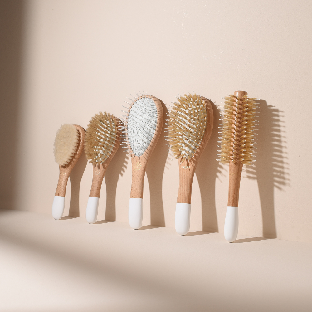 Collection de cinq brosses à cheveux Bachca sur fond rose pâle : brushing, brillance, volume, cheveux fins et brosse bébé en soie de chèvre.