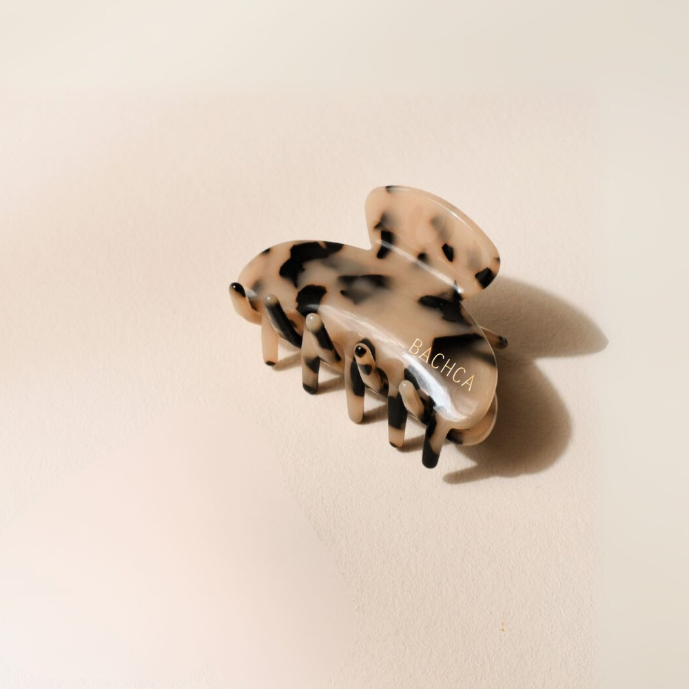 Pince à cheveux motif écaille taille moyenne de la marque Bachca, présentée sur fond rose pâle.