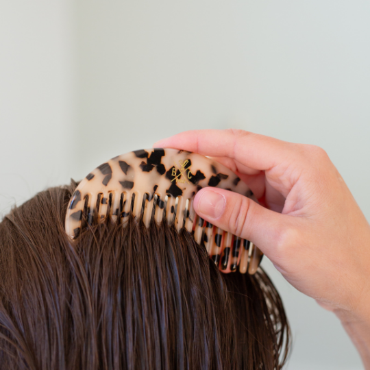 Femme démêlant ses cheveux mouillés avec un peigne demi-lune écaille Bachca, accessoire élégant et pratique.