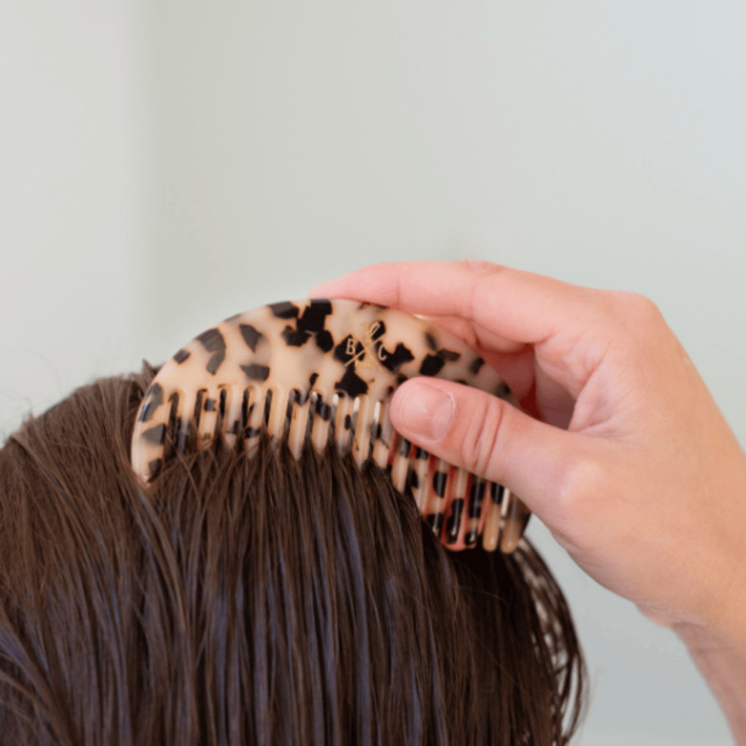 Peigne écaille Bachca en acétate de cellulose utilisé sur cheveux mouillés, tenu à la main pour un démêlage tout en douceur.