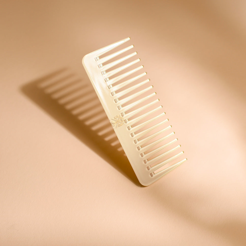 Peigne Bachca en acétate coloris ivoire, présenté debout avec son ombre portée, photographié sur une surface beige.