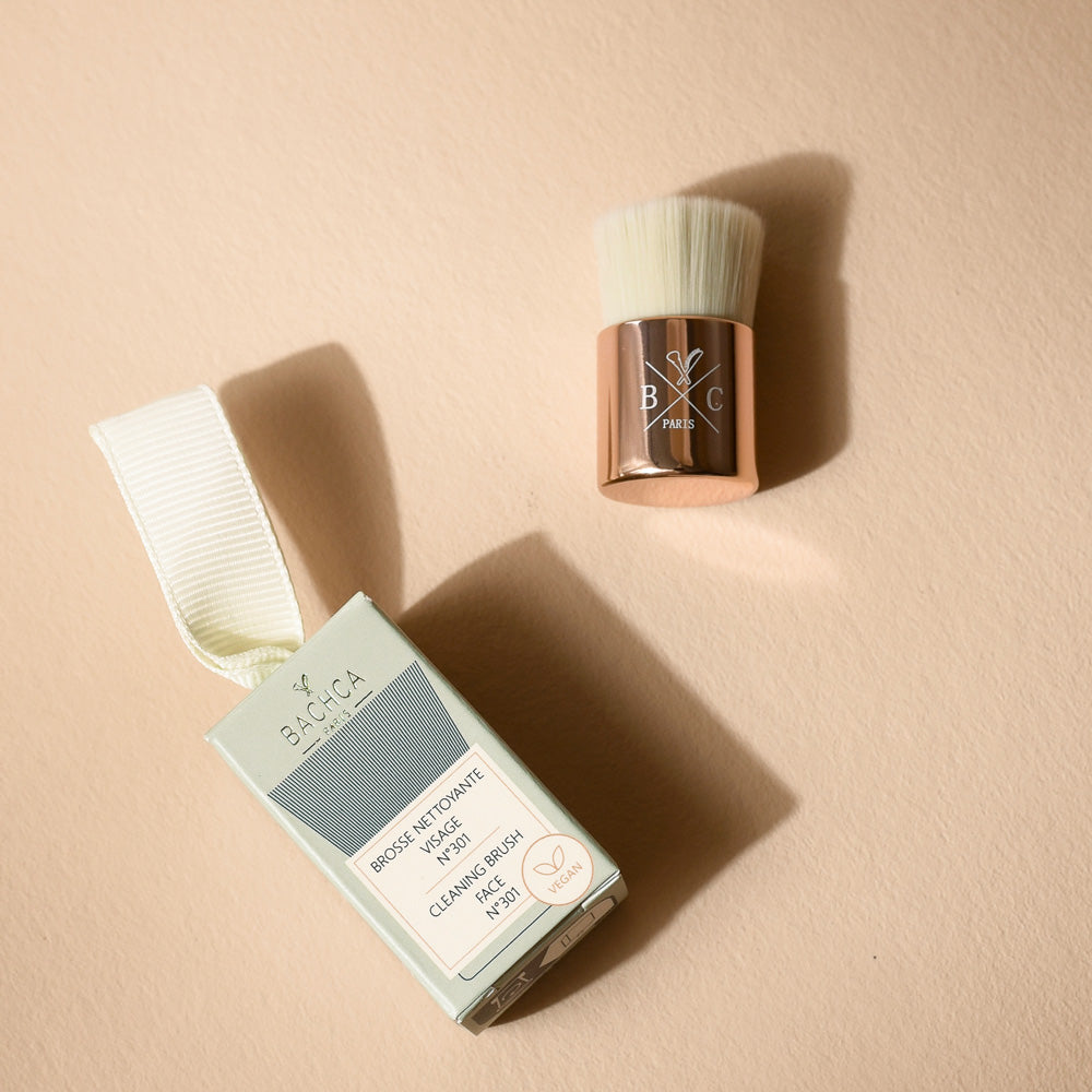 Petite brosse nettoyante visage Bachca avec poils ultra-doux, idéale pour éliminer impuretés et maquillage, accompagnée de son étui élégant.