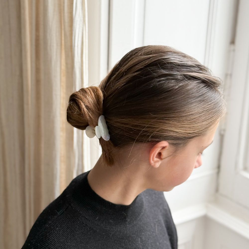 Femme de dos avec un chignon maintenu par une petite pince nacrée Bachca, look élégant et naturel.