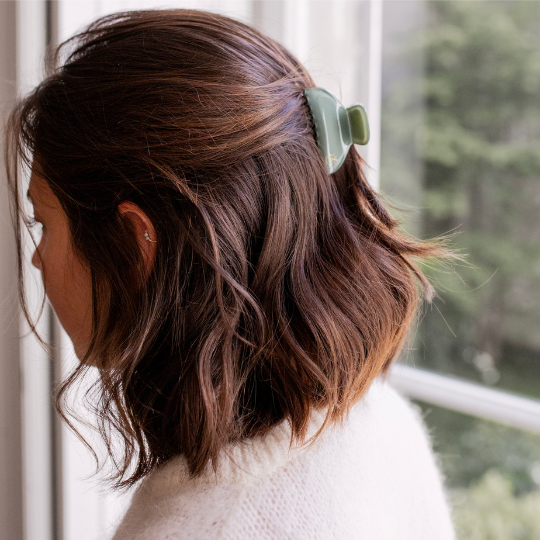 Petite pince vert d’eau Bachca fixant une demi-queue sur cheveux mi-longs, pour un look naturel et raffiné.