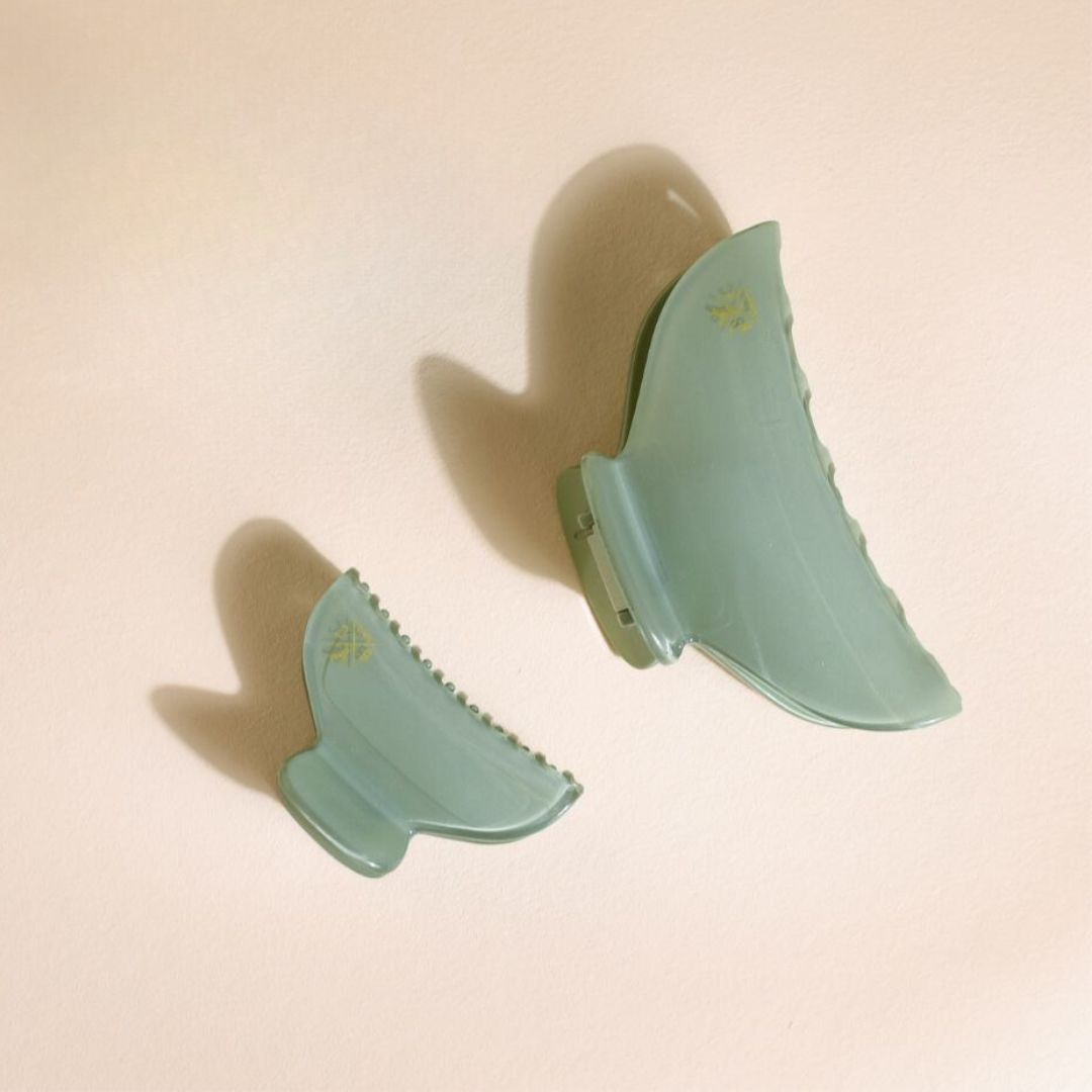 Pinces à cheveux Bachca vert d’eau en deux tailles, une grande et une petite, posées côte à côte sur un fond beige, avec ombres douces projetées par la lumière naturelle.
