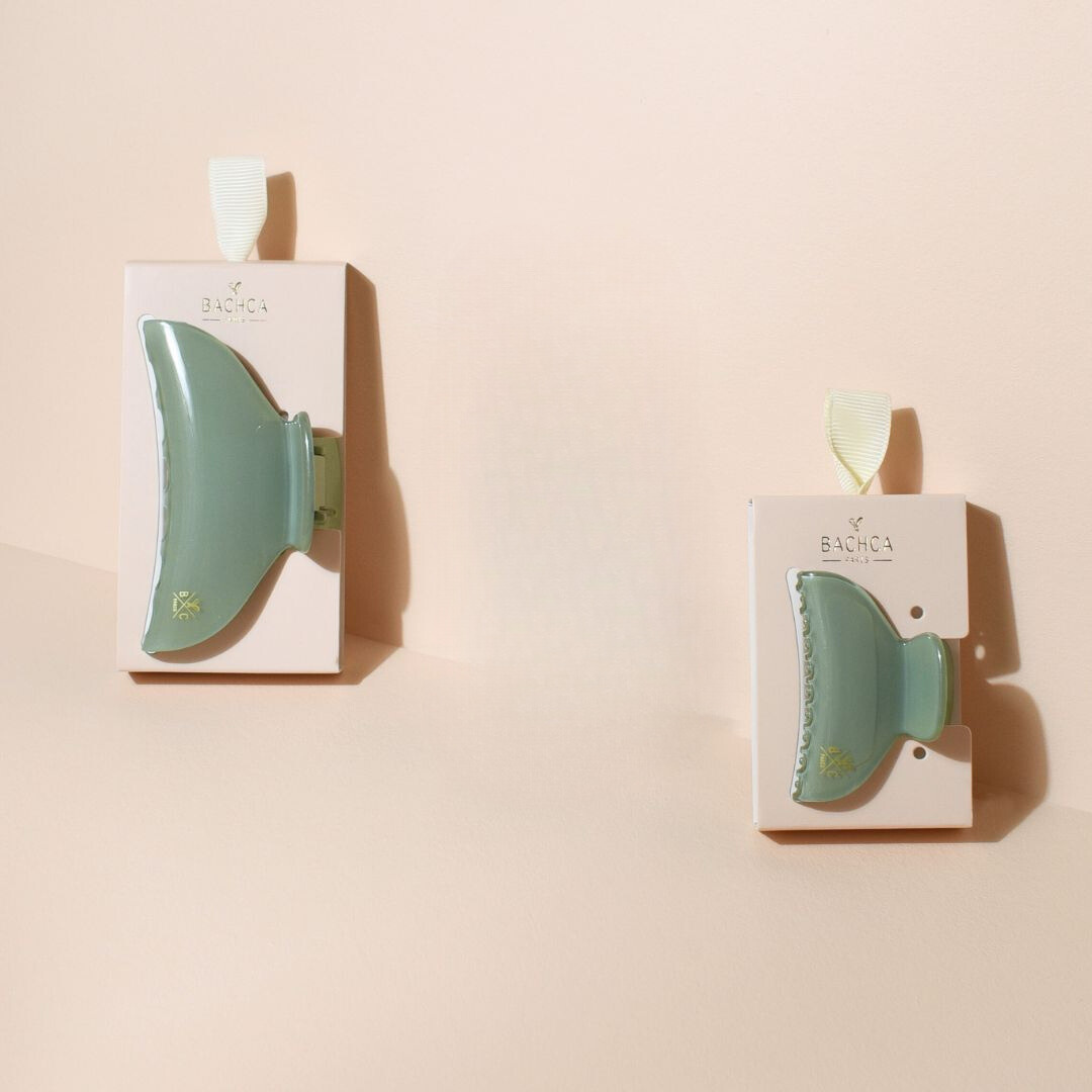 Deux pinces à cheveux Bachca vert d’eau, une grande et une petite, présentées sur leur carton d’emballage respectif, posées sur un fond beige doux avec éclairage naturel.