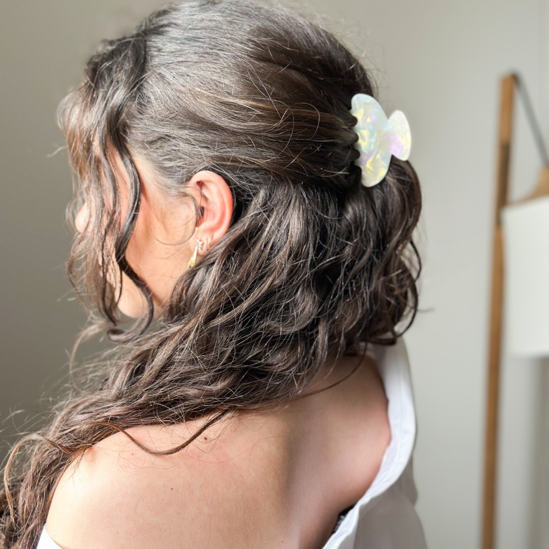 Cheveux ondulés attachés avec une pince à cheveux nacrée BACHCA, coiffure semi-attachée élégante.