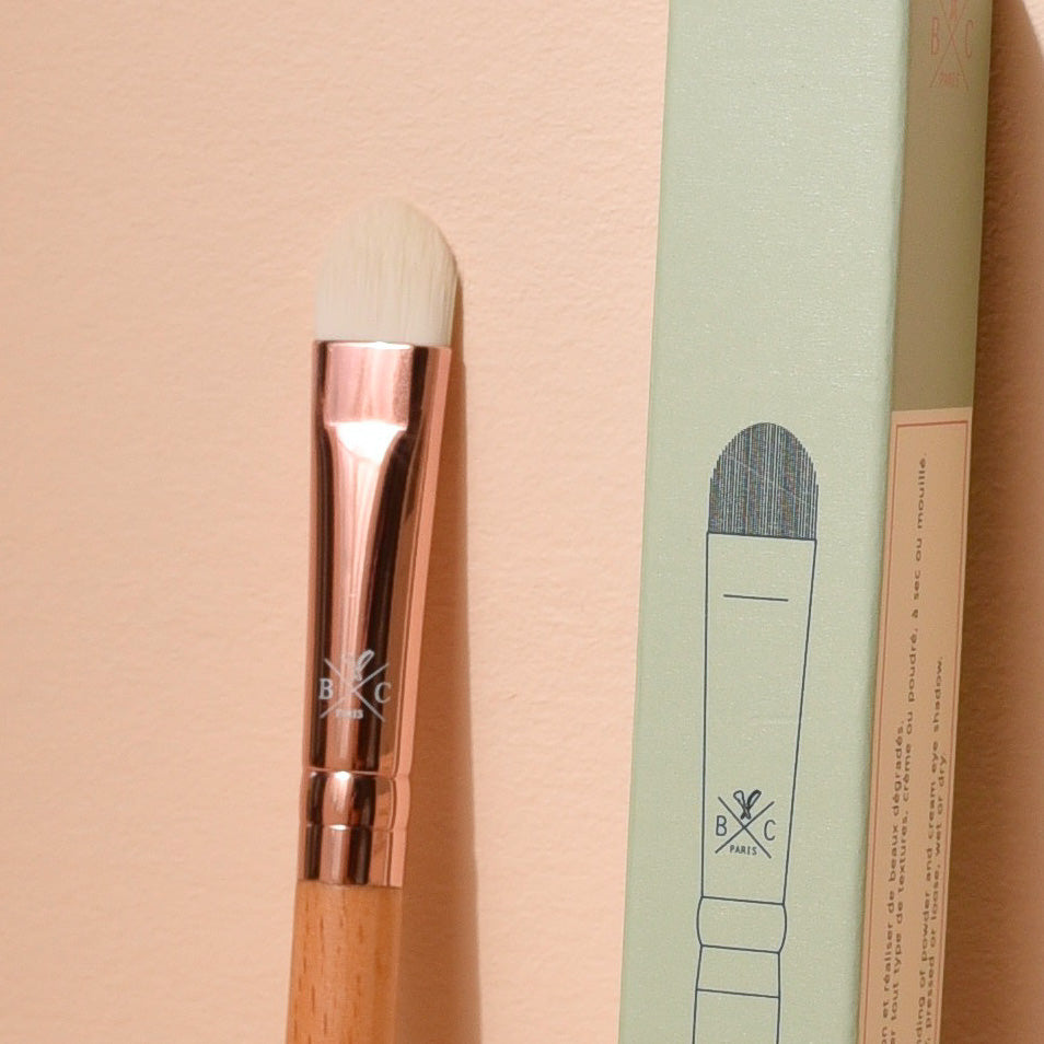 Pinceau précision Bachca avec manche en bois de hêtre et embout rosé, présenté avec son étui vert pastel, idéal pour appliquer les fards à paupières.