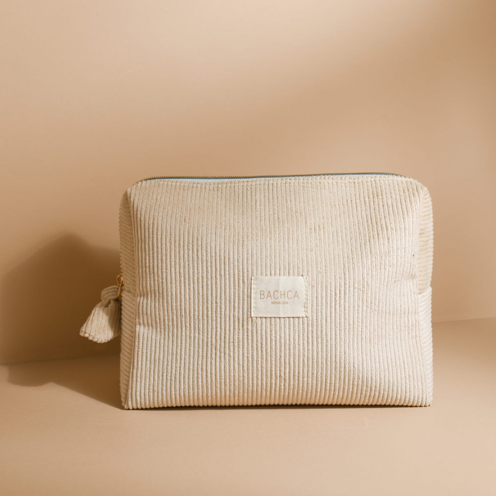 Trousse de toilette BACHCA en velours côtelé beige sable, sur fond uni, lumière naturelle douce.