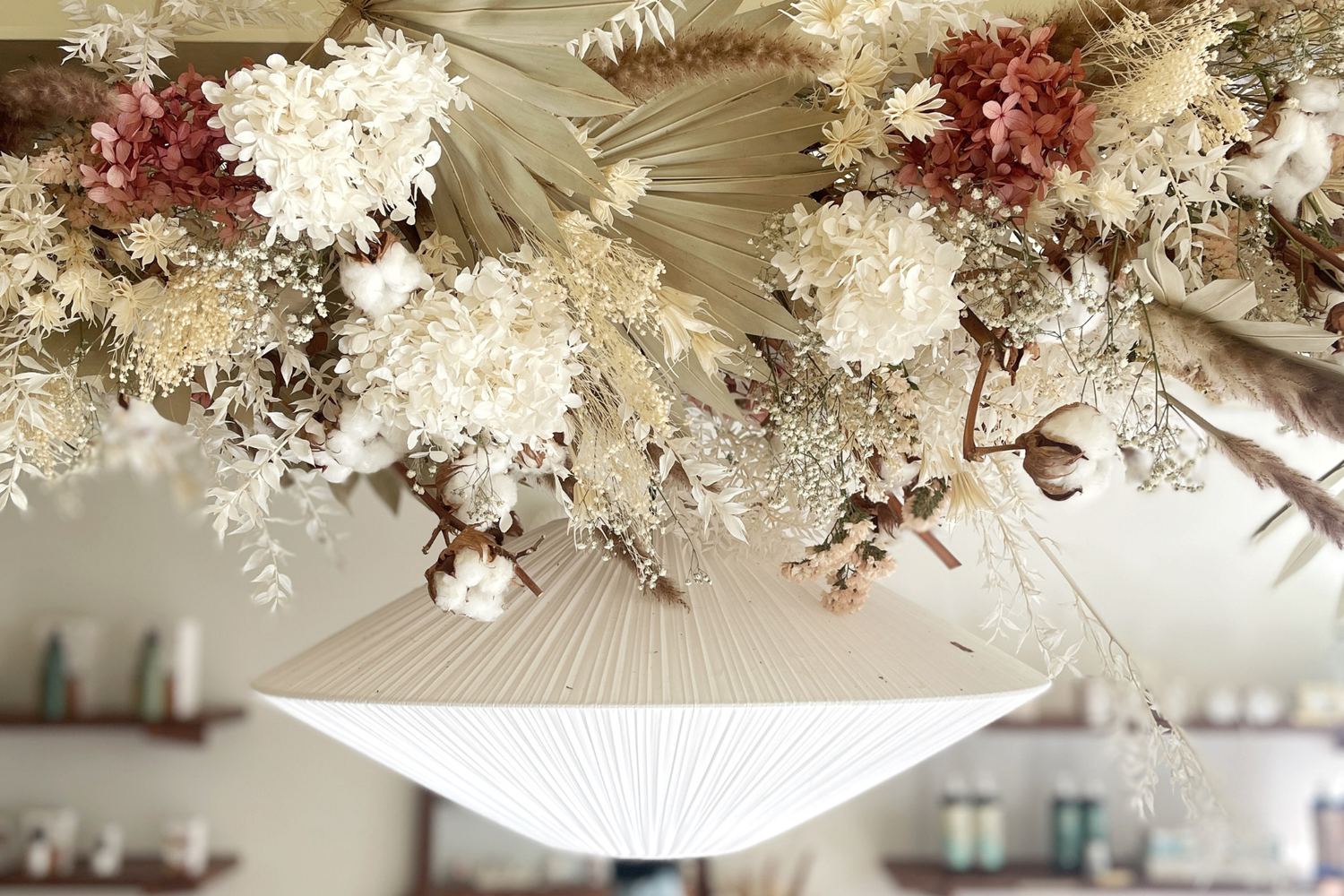 Gros plan sur un luminaire décoré de fleurs séchées visible dans la boutique nantaise Bachca.