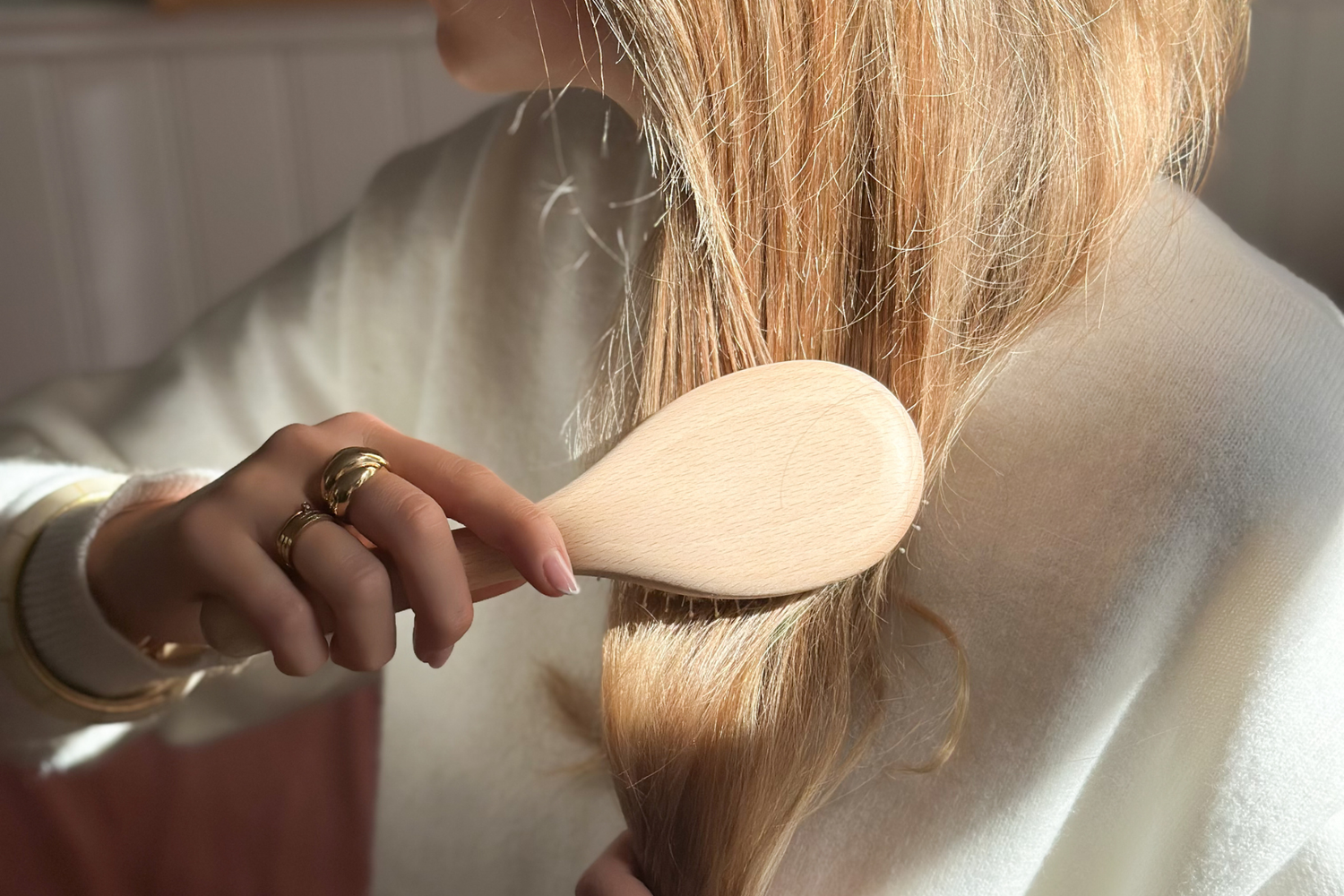 Jeune femme de profil blonde se brossant les cheveux à l'aide d'une brosse à cheveux Bachca.