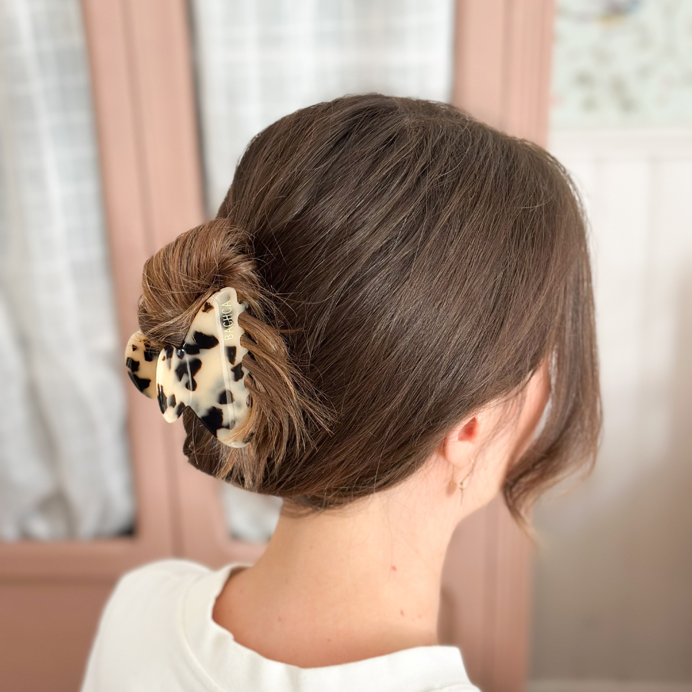 Grande barrette à cheveux écaille portée sur cheveux bruns.
