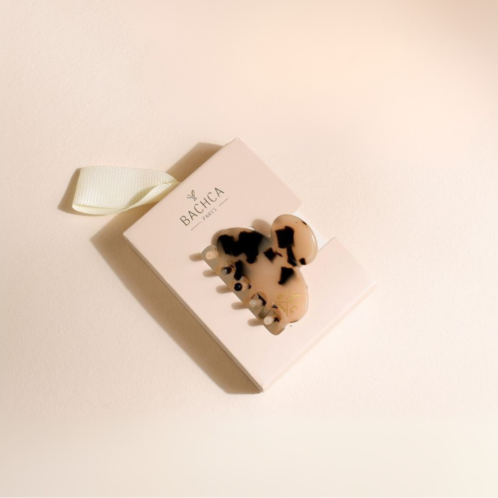 Petite pince à cheveux écaille de la marque Bachca sur fond studio rose poudré.