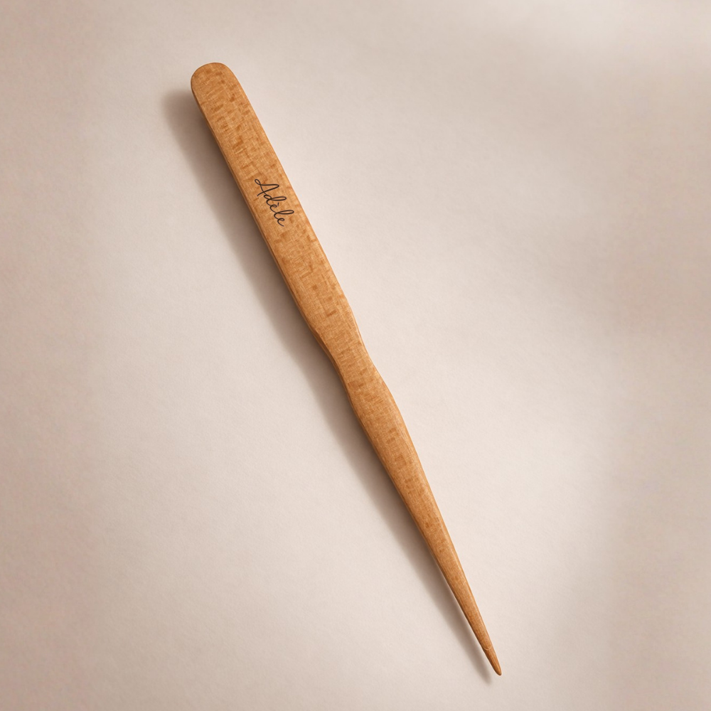 Brosse à cheveux plaquage de la marque Bachca sur un fond studio beige, vue de dos avec une gravure sur bois " Adèle".