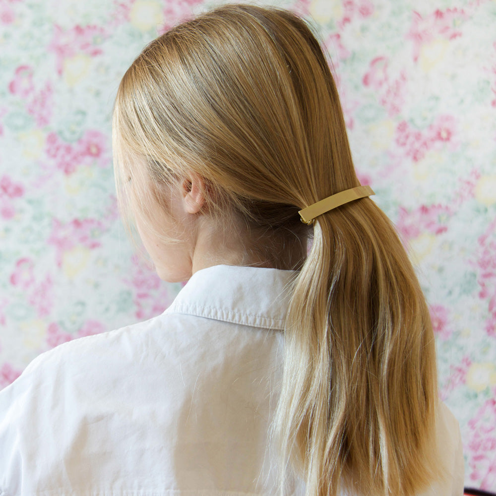 Barrette bijou Bachca en métal doré, accessoire cheveux élégant pour attacher une demi-queue sur cheveux blonds, style chic et minimaliste.