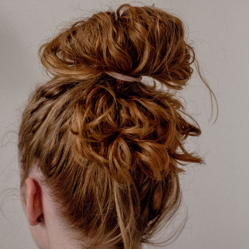 Chignon haut maintenu avec un élastique cheveux pastel Bachca, accessoire solide et discret idéal pour attacher les cheveux longs et épais.