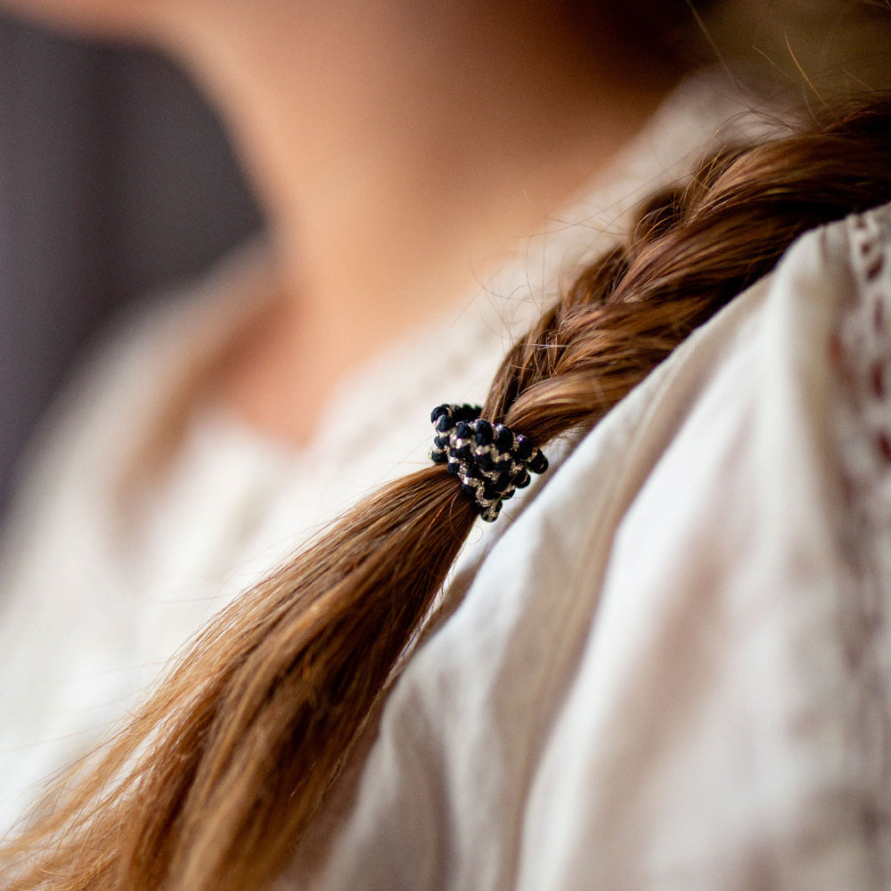 Élastique cheveux épais noir Bachca utilisé pour attacher une tresse, accessoire pratique et élégant qui maintient parfaitement les coiffures.
