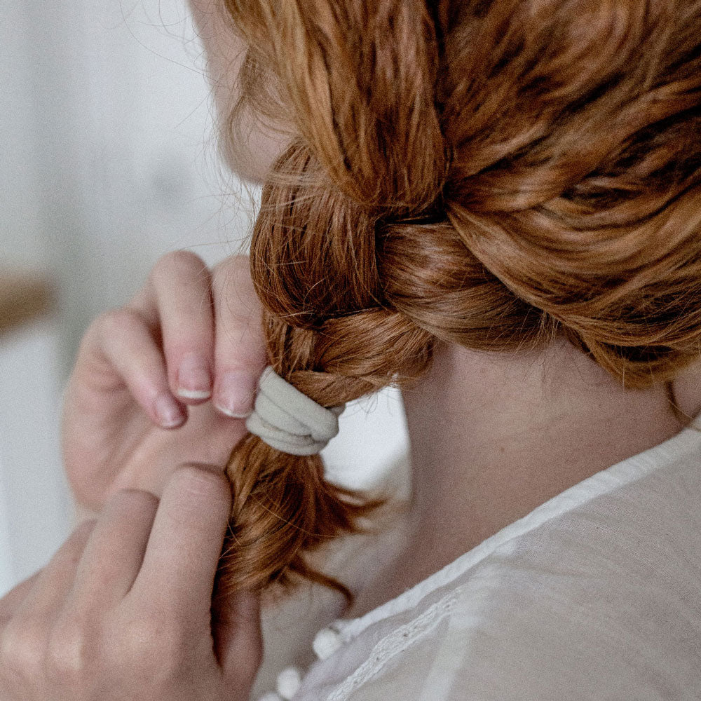 Élastique cheveux sans couture Bachca en beige, utilisé pour attacher une tresse sur cheveux roux, accessoire discret et confortable au quotidien.