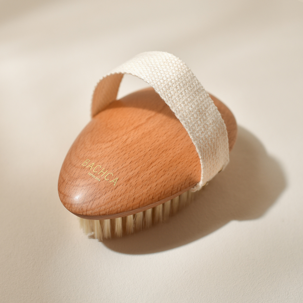 Photo studio sur fond beige, le produit mis en avant est la brosse de massage à sec Bachca, la brosse est en bois de hêtre, les poils sont en soie de sanglier.