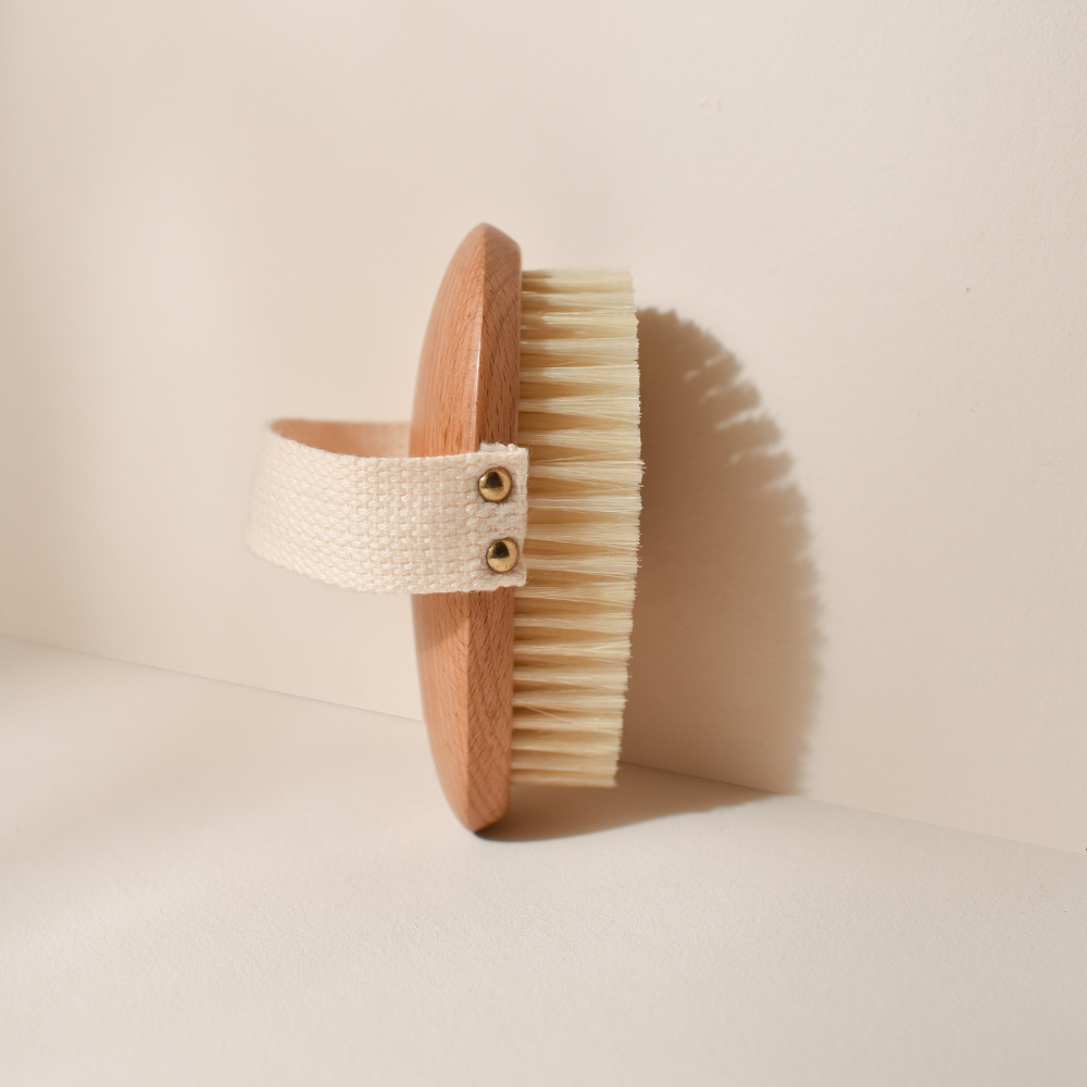 Photo studio sur fond beige, le produit mis en avant est la brosse de massage à sec Bachca, la brosse est en bois de hêtre, les poils sont en soie de sanglier.