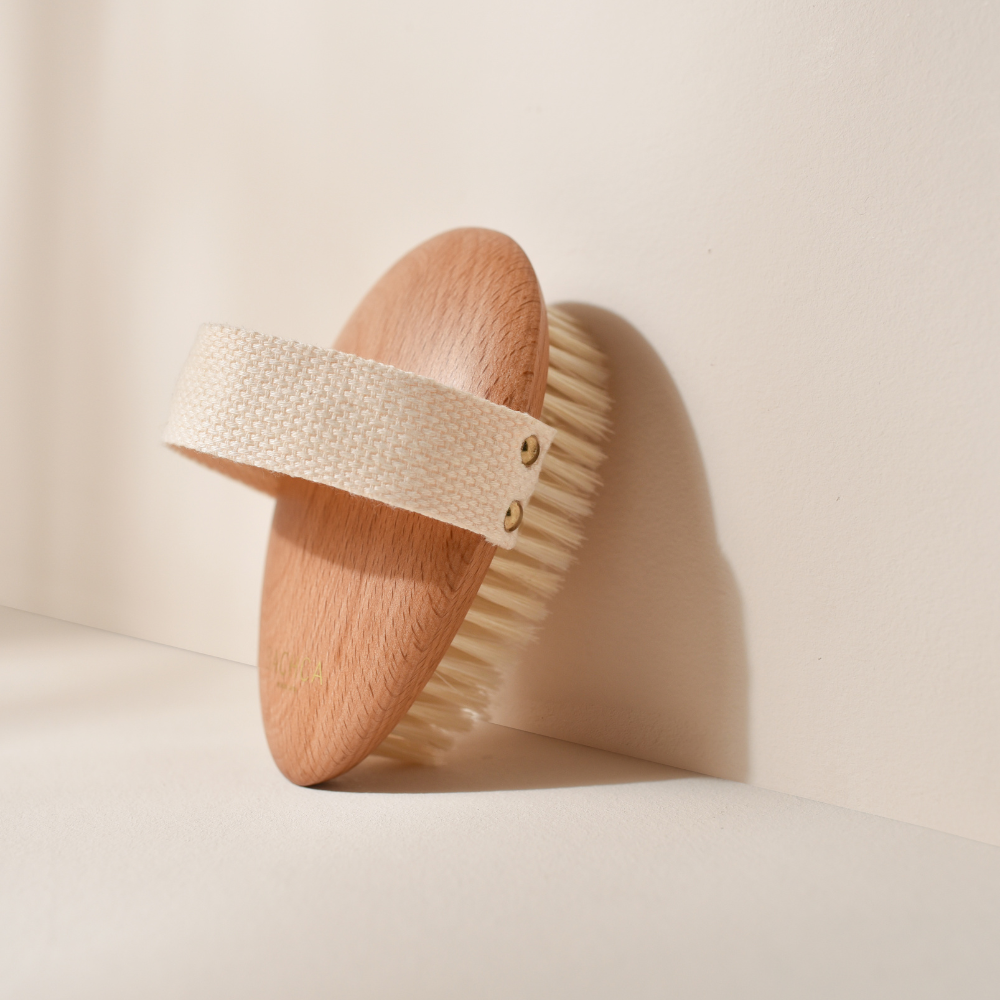 Photo studio sur fond beige, le produit mis en avant est la brosse de massage à sec Bachca, la brosse est en bois de hêtre, les poils sont en soie de sanglier.