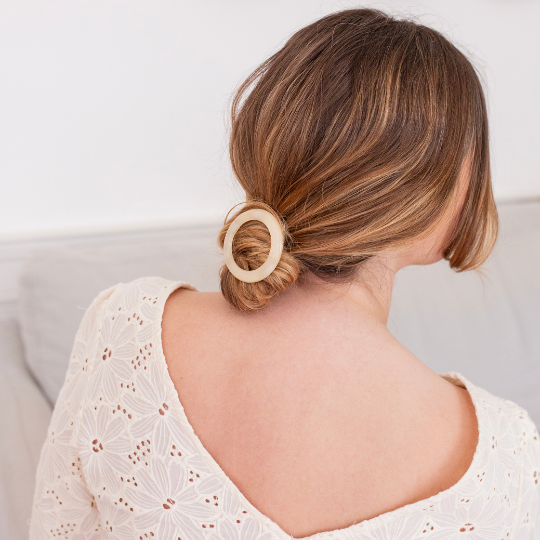 Chignon bas élégant maintenu par une barrette ronde ivoire Bachca, coiffure naturelle et raffinée.
