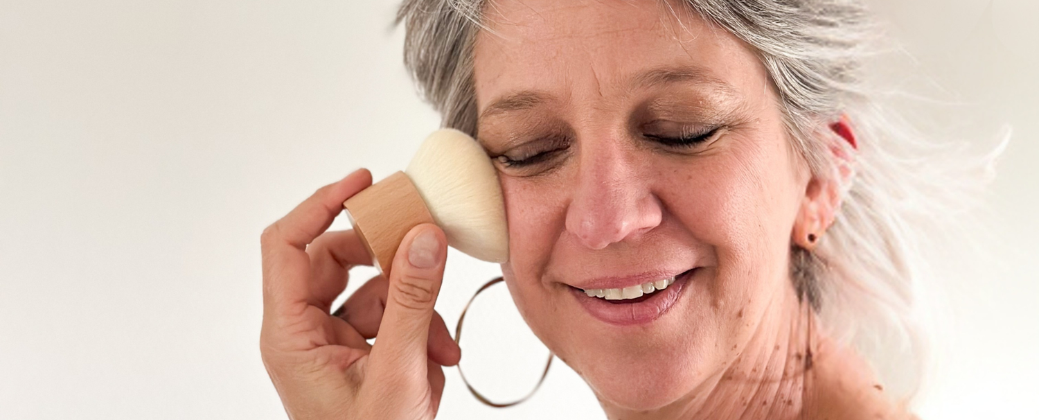 Femme souriant en utilisant sur son visage le pinceau à maquillage kabuki de la marque Bachca.